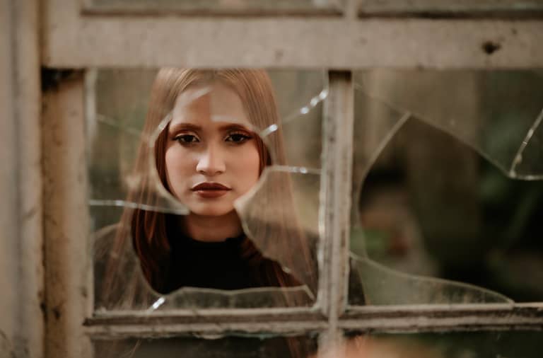 Woman looking through a broken window of a rental property