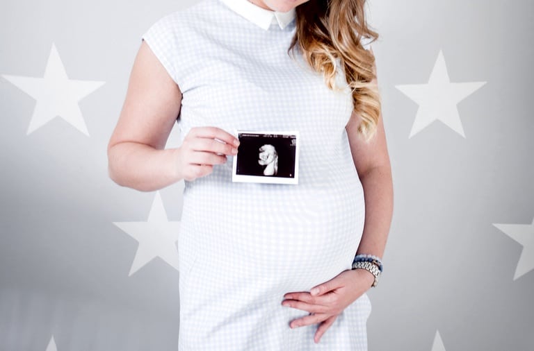 Pregnant woman holding photograph of scan