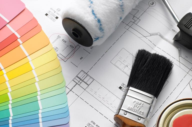 A paint palette and paint brush on top of a blueprint, suggesting the best paint colours for a rental property.